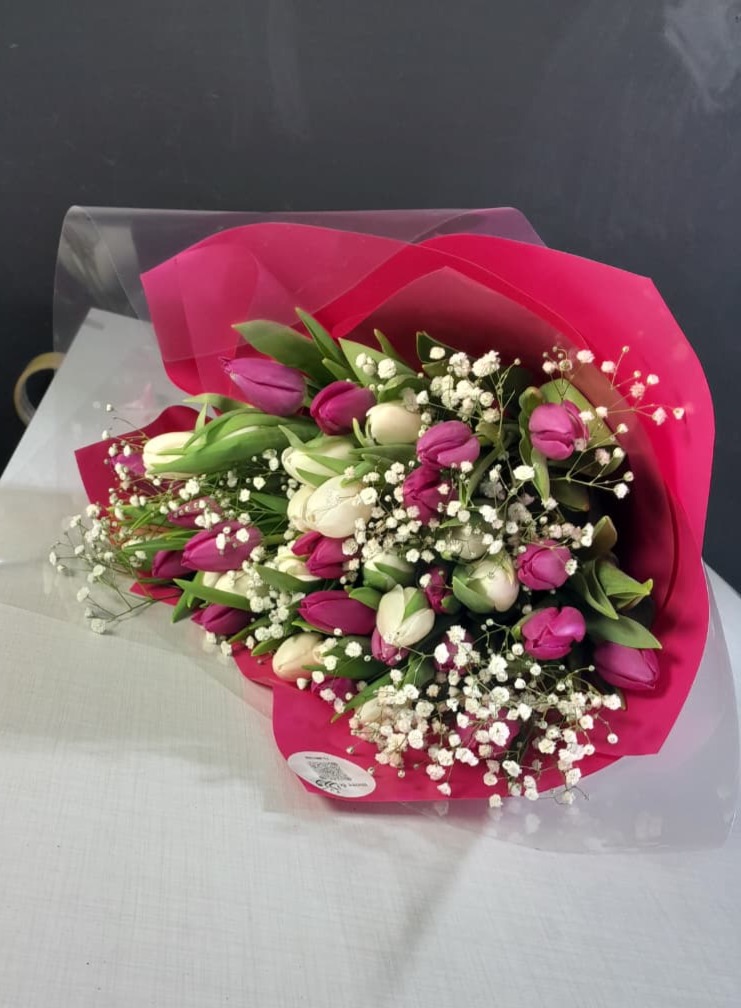 Purple and white tulips with baby's breath in pink wrapper